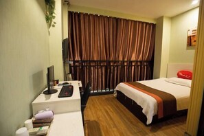 Habitación de hotel con escritorio, cama, televisión y ventana con cortinas.