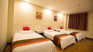 A hotel room with three beds, each with a red pillow and a white headboard. There are two wall-mounted artworks and a window with curtains. - Shushi Hotel (Shiyan)
