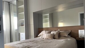 Un dormitorio moderno con una cama grande, cabecera de madera y estanterías empotradas.