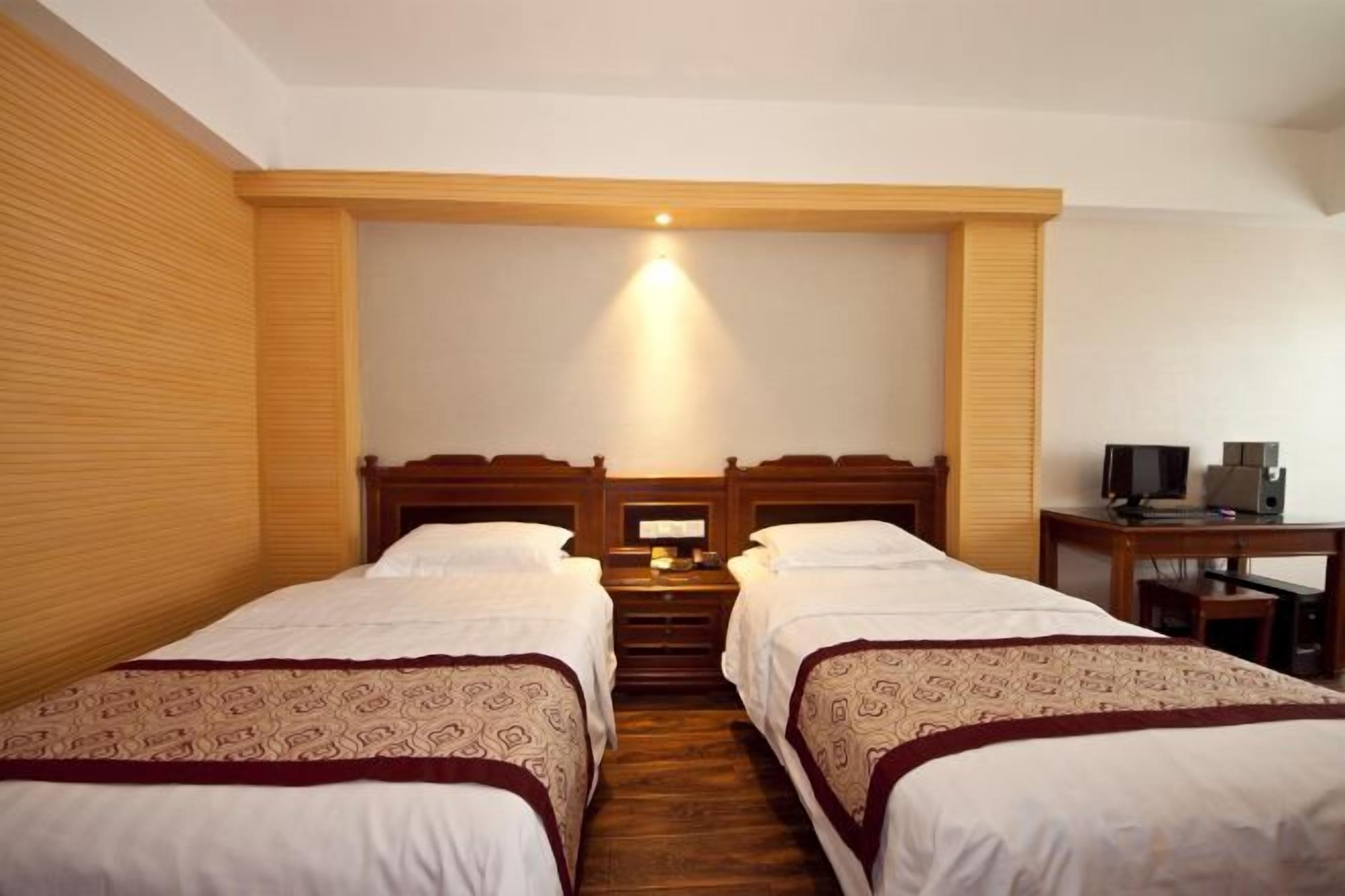 A hotel room with two beds, a desk with a computer, and a television.