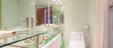 A modern bathroom with a glass-enclosed shower, a white toilet, and a glass vanity.