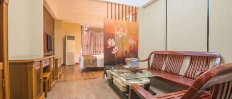 Una sala de estar con un sofá, una mesa de centro de vidrio y muebles de madera.
