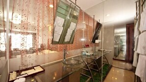 Une salle de bain moderne avec un meuble-lavabo en verre, un grand miroir et un sol recouvert d’un gazon artificiel vert.