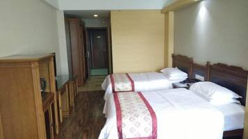 Habitación de hotel con dos camas, muebles de madera y un pasillo que lleva a una puerta.