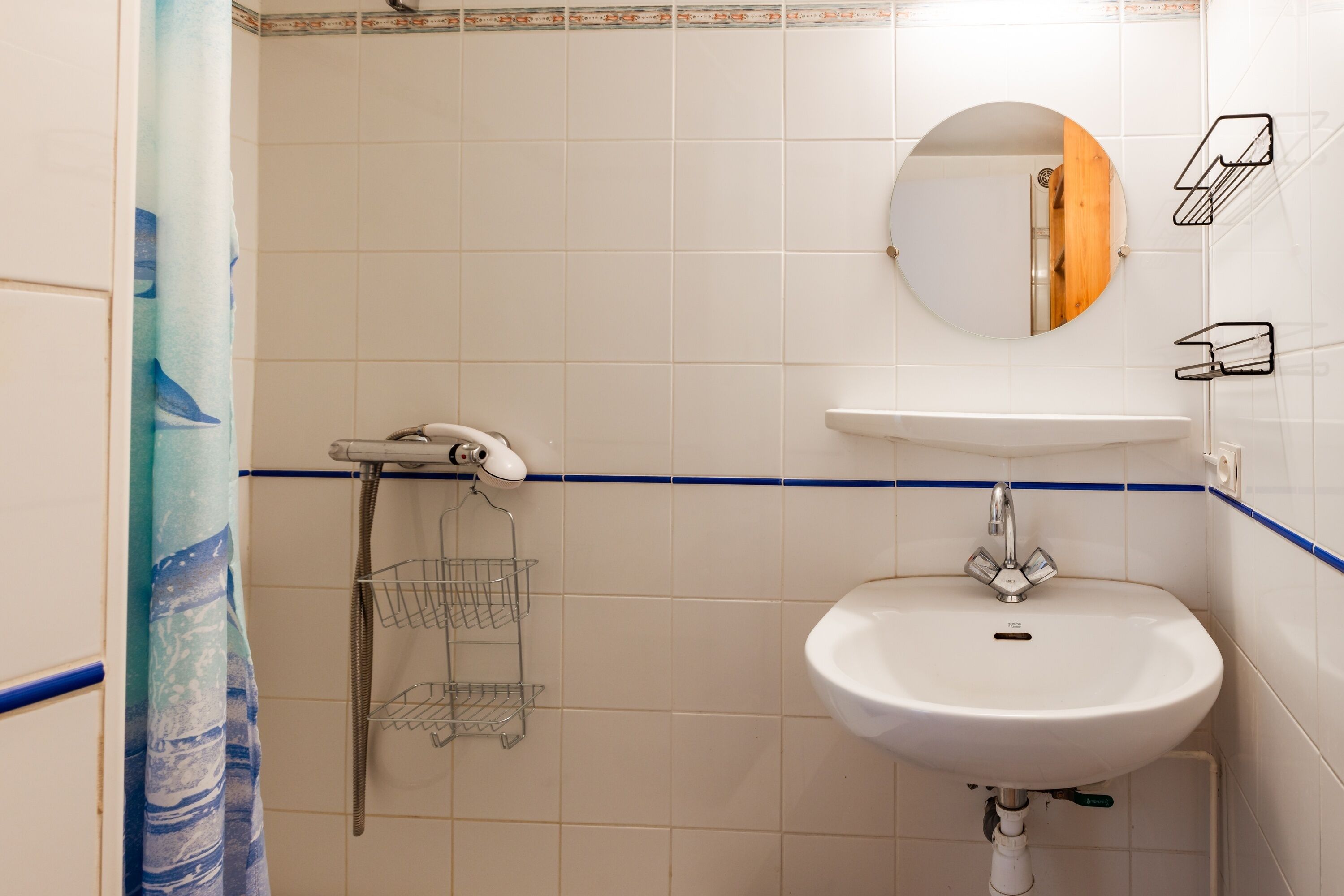 Ein Badezimmer mit einem weißen Waschbecken, einem Spiegel und einer Dusche.