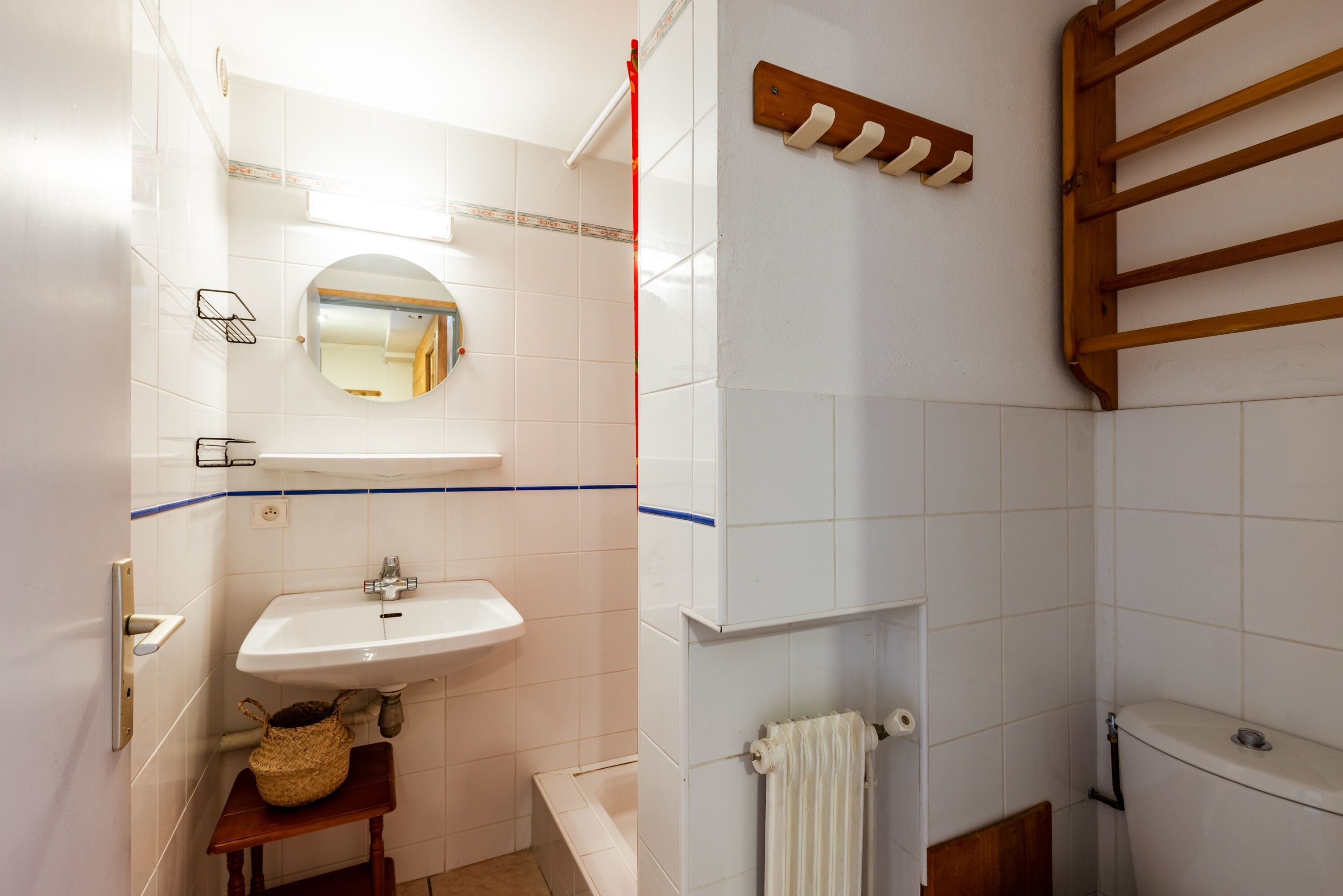 Een badkamer met een wastafel, spiegel en houten handdoekhouder.