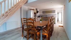 A modern kitchen with a wooden staircase, a dining table with chairs, and a view of the adjacent living area. - Mangoero - Four Bedroom House, Sleeps 12 (Plumergat)