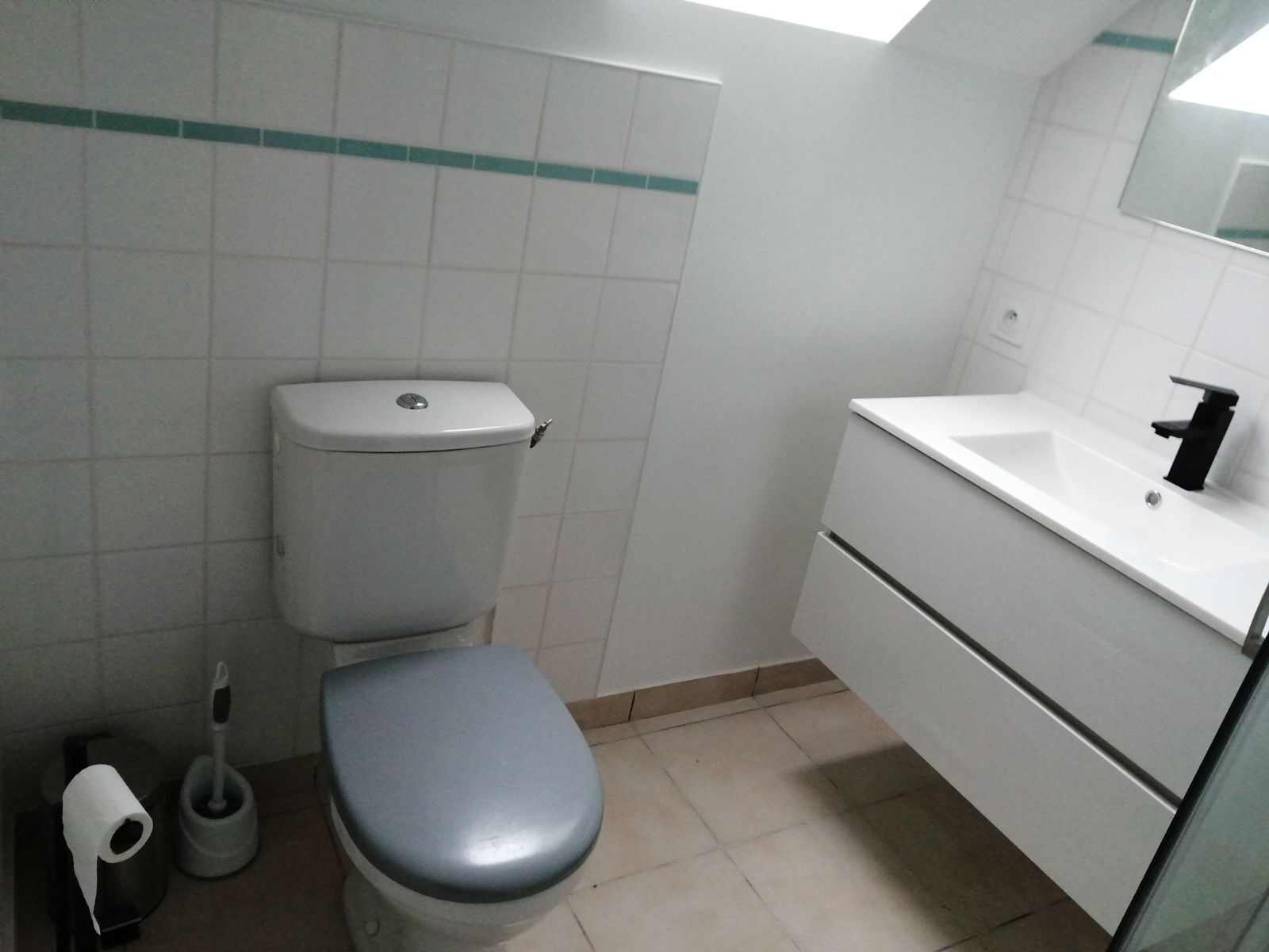 Une salle de bain avec des toilettes, un lavabo et un miroir.
