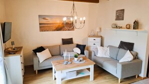 Ein gemütliches Wohnzimmer mit einem grauen Sofa, einem Holztisch und einer Deckenleuchte.