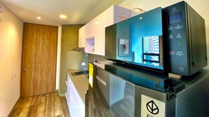 Eine moderne Küche mit Einbaukühlschrank, einer Mikrowelle und einem großen Flachbildfernseher.