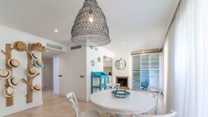 Un coin repas avec une table ronde, des chaises blanches et un luminaire suspendu.