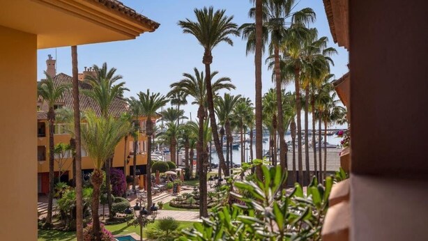 Une cour intérieure agrémentée de palmiers, une piscine et une vue sur le port de plaisance.