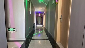 A hotel hallway with a black and white tiled floor, directional signs, and a neon light strip on the ceiling. - Kunshan Youjian Hotel (Huaqiao Huaxi Park Subway Station) (Kunshan)