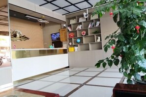 A reception area with a reception desk, a television, and a plant. - Kunshan Youjian Hotel (Huaqiao Huaxi Park Subway Station) (Kunshan)