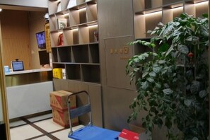 A reception area with a desk, shelves, and a potted plant.