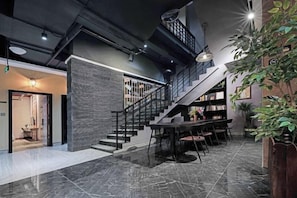 Een modern interieur met een trap, een eethoek en een boekenkast.