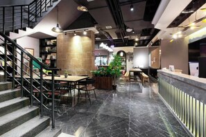 Un interior moderno con mostrador de recepción, zona de estar y escalera.
