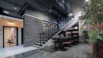 A modern interior with a staircase, a dining area, and a bookshelf.