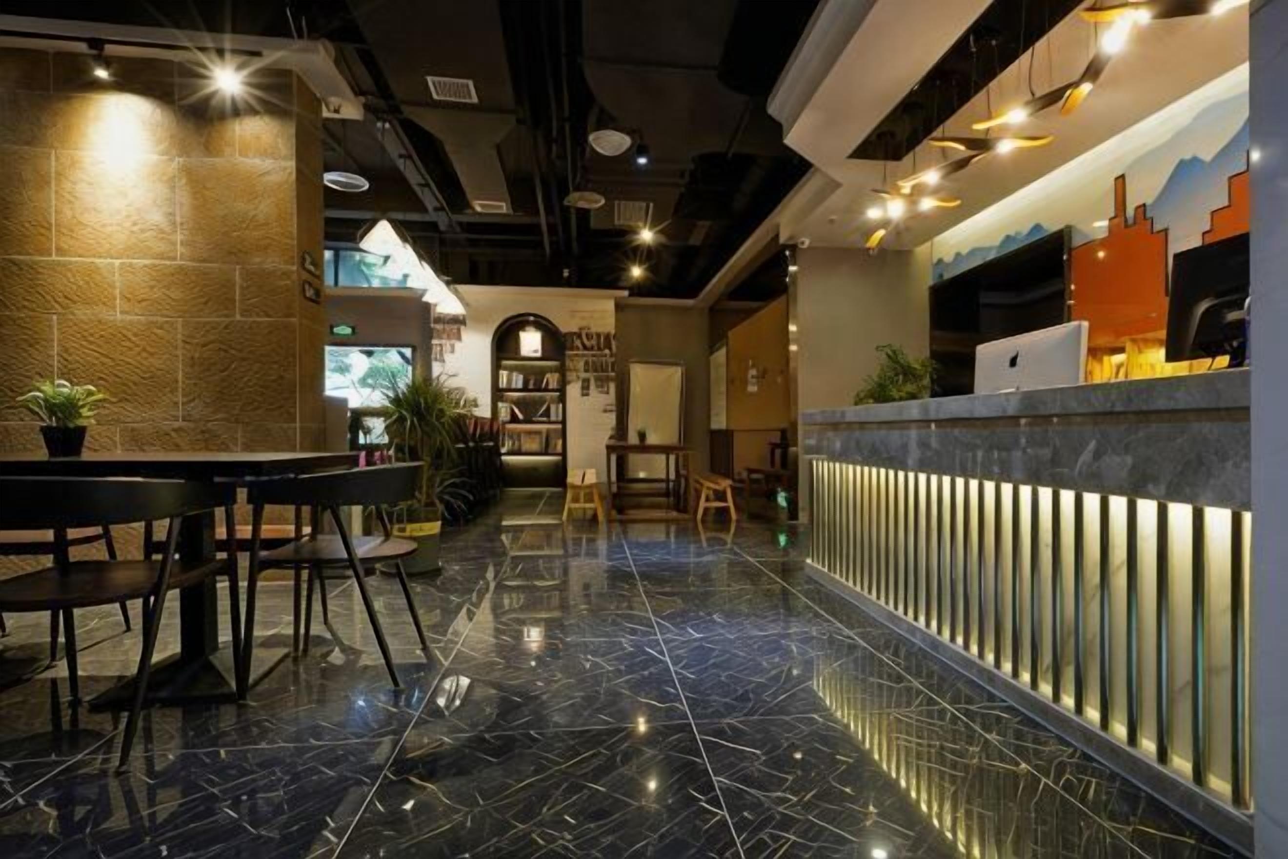 A modern hotel lobby with a marble floor, a reception desk, seating area, and a bookshelf.