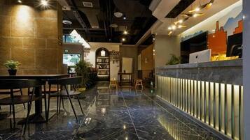 A modern hotel lobby with a marble floor, a reception desk, seating area, and a bookshelf.