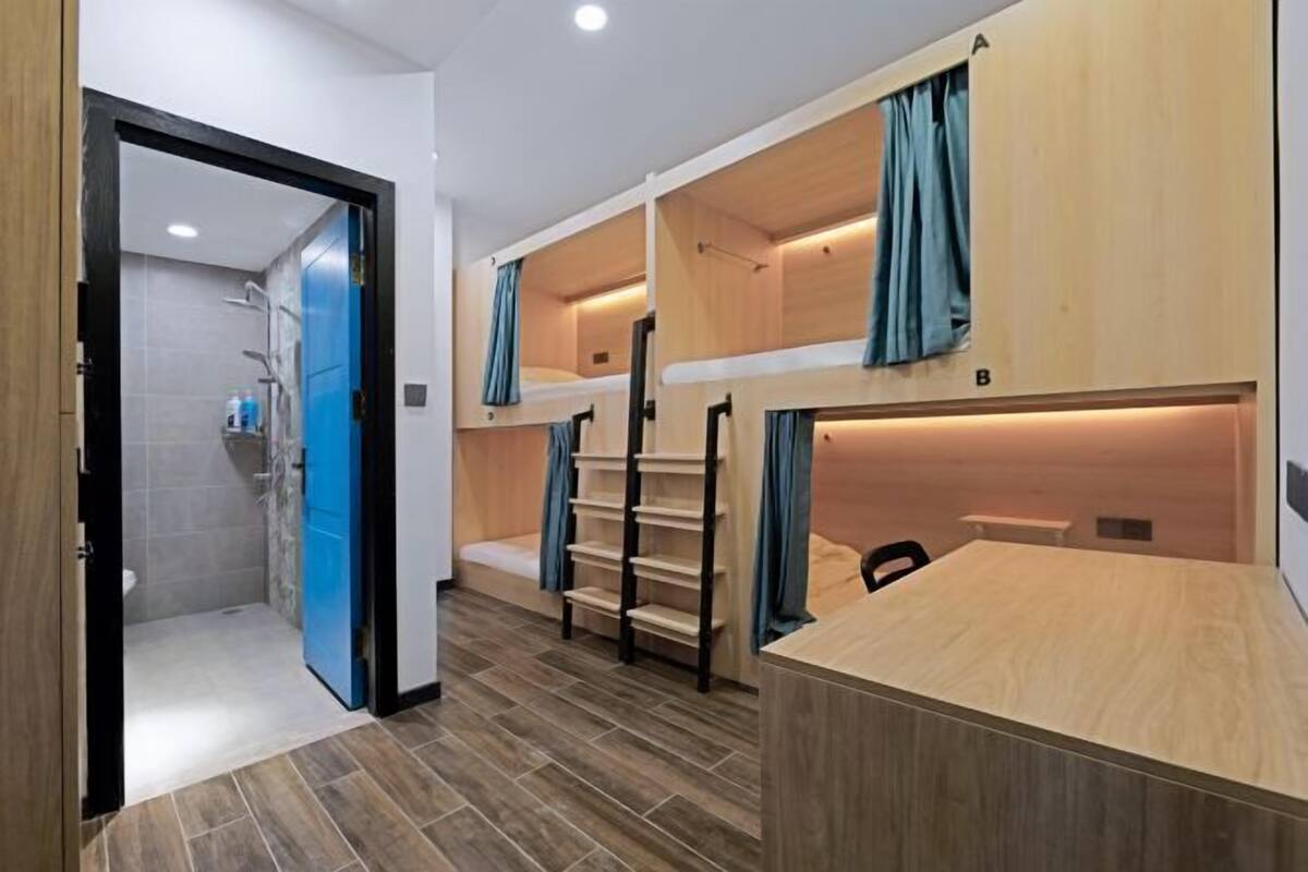 Ein Zimmer mit Etagenbetten, einem Schreibtisch und einem Duschbereich.