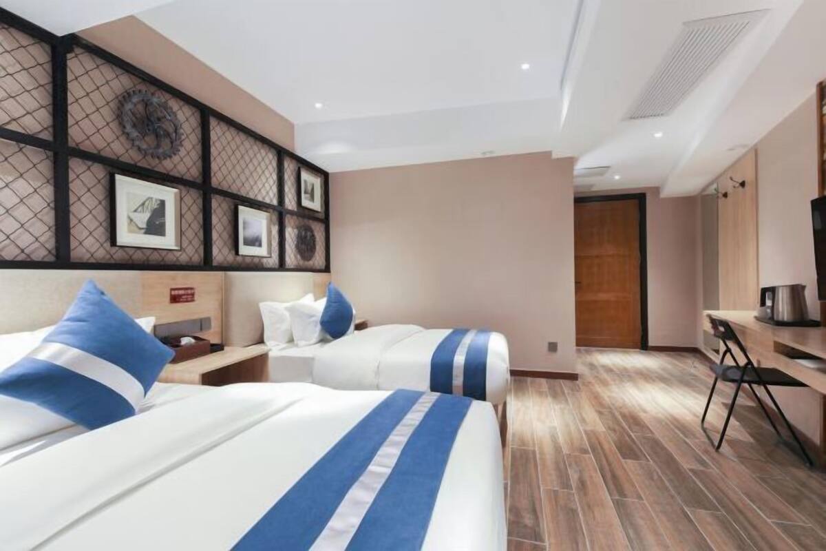 Ein Hotelzimmer mit zwei Betten, einem Schreibtisch und einer Küchenzeile.