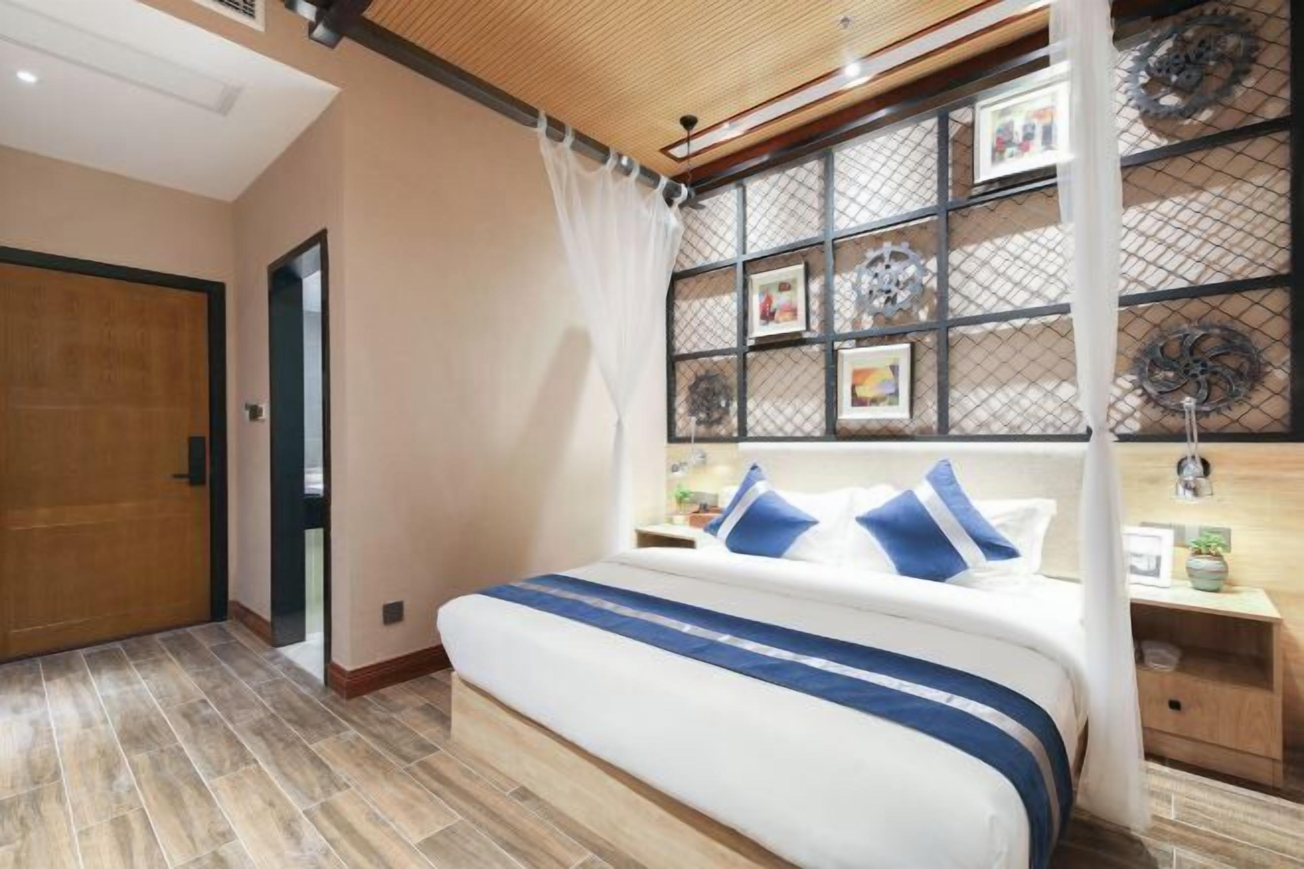 A bedroom with a bed, a nightstand, a window with a curtain, and a wooden ceiling.
