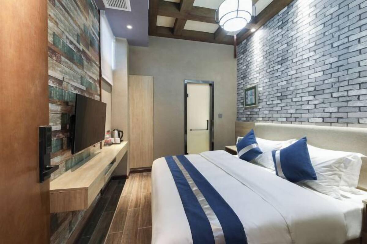 Ein Hotelzimmer mit einem Bett, einem Fernseher, einer Holzkabine und einer Backsteinwand.