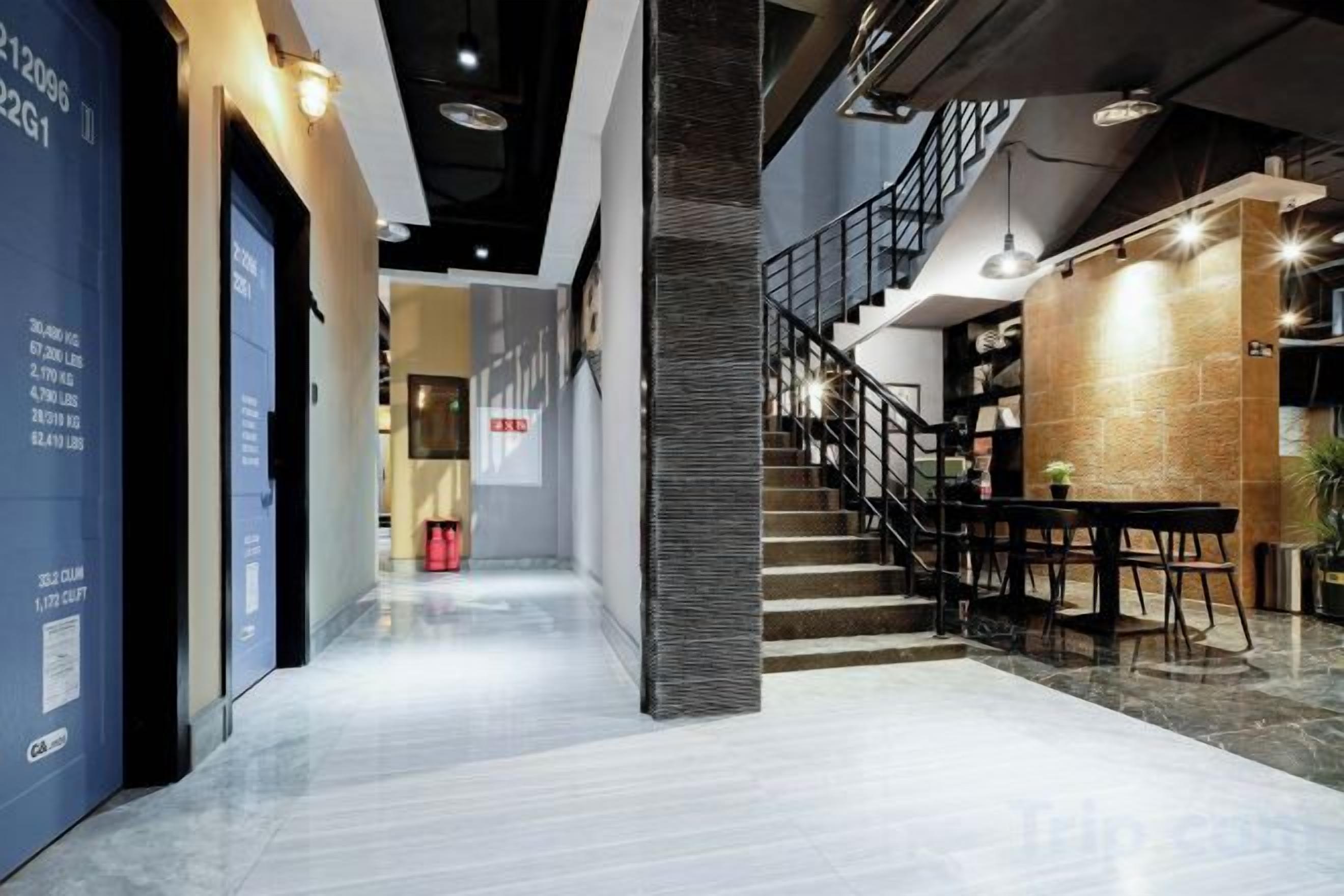 A modern interior with a staircase, a seating area, and a hallway leading to a door.
