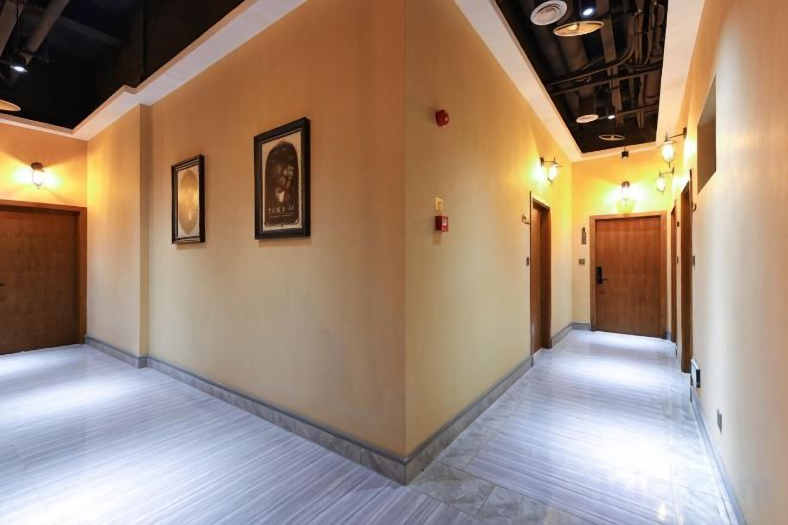 A hallway with two doors, framed artwork on the walls, and a light fixture on the ceiling.
