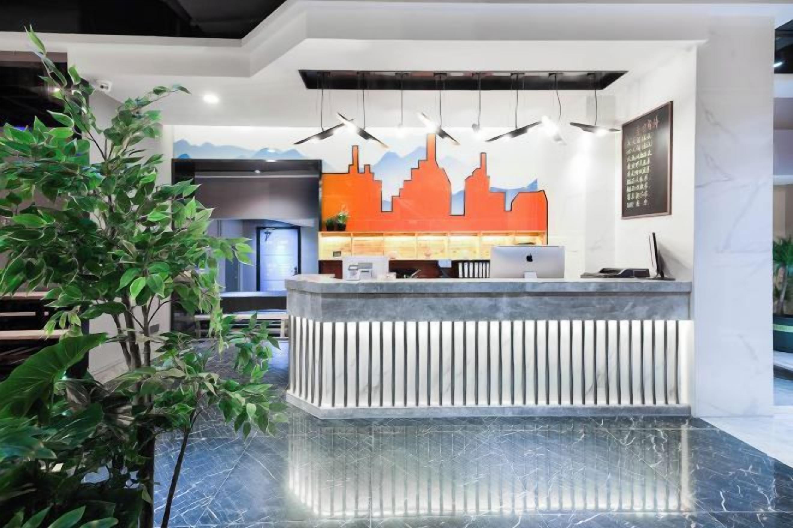A reception desk with a cityscape mural, a plant, and a marble floor.