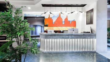 A reception desk with a cityscape mural, a plant, and a marble floor.