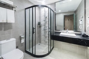 A modern bathroom with a glass-enclosed shower, a white toilet, a black marble sink, and a large mirror. - Zou Qu Ye Travel Hotel (Chongqing)