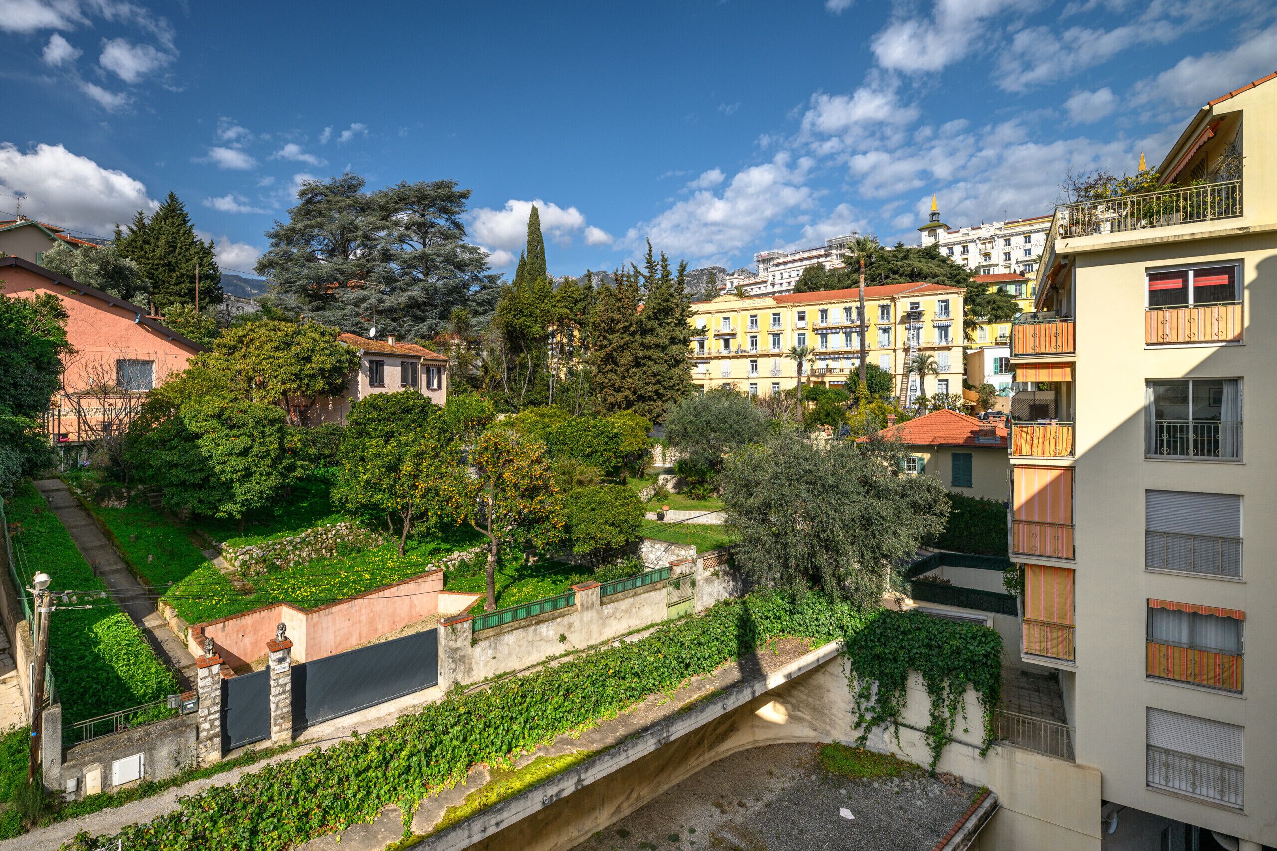 A residential area with a narrow waterway, buildings with balconies, and greenery.