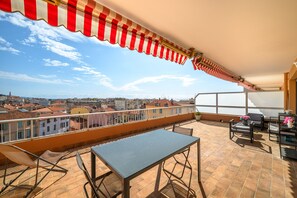 Enjoy breathtaking views of the city from this balcony with a tiled floor, metal table, and chair.