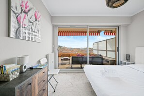 Relax in a serene space with a large bed, bedside table, and desk area, plus an outdoor terrace with seating.