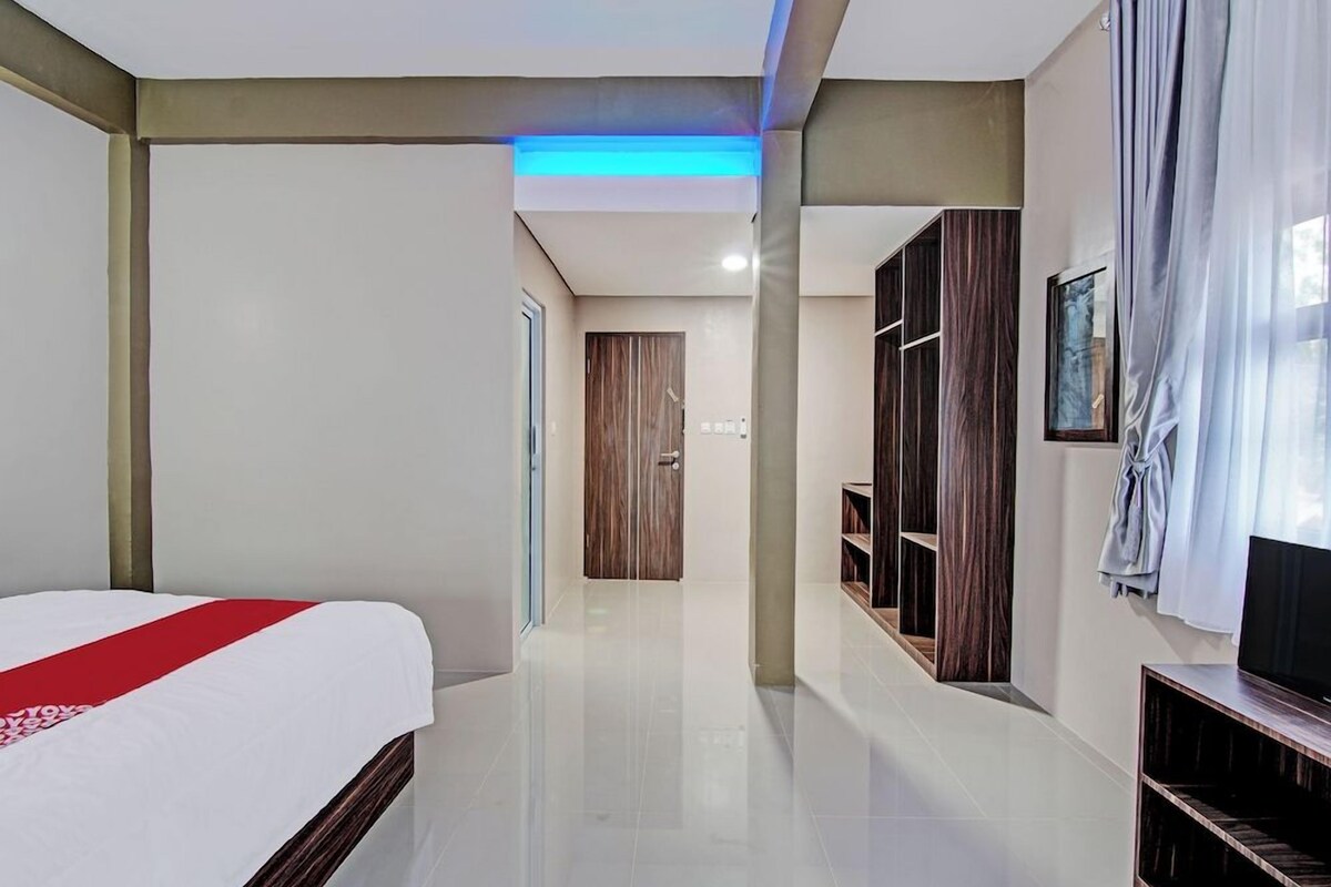 Una habitación de hotel con cama, televisión, armario y baño a la vista.