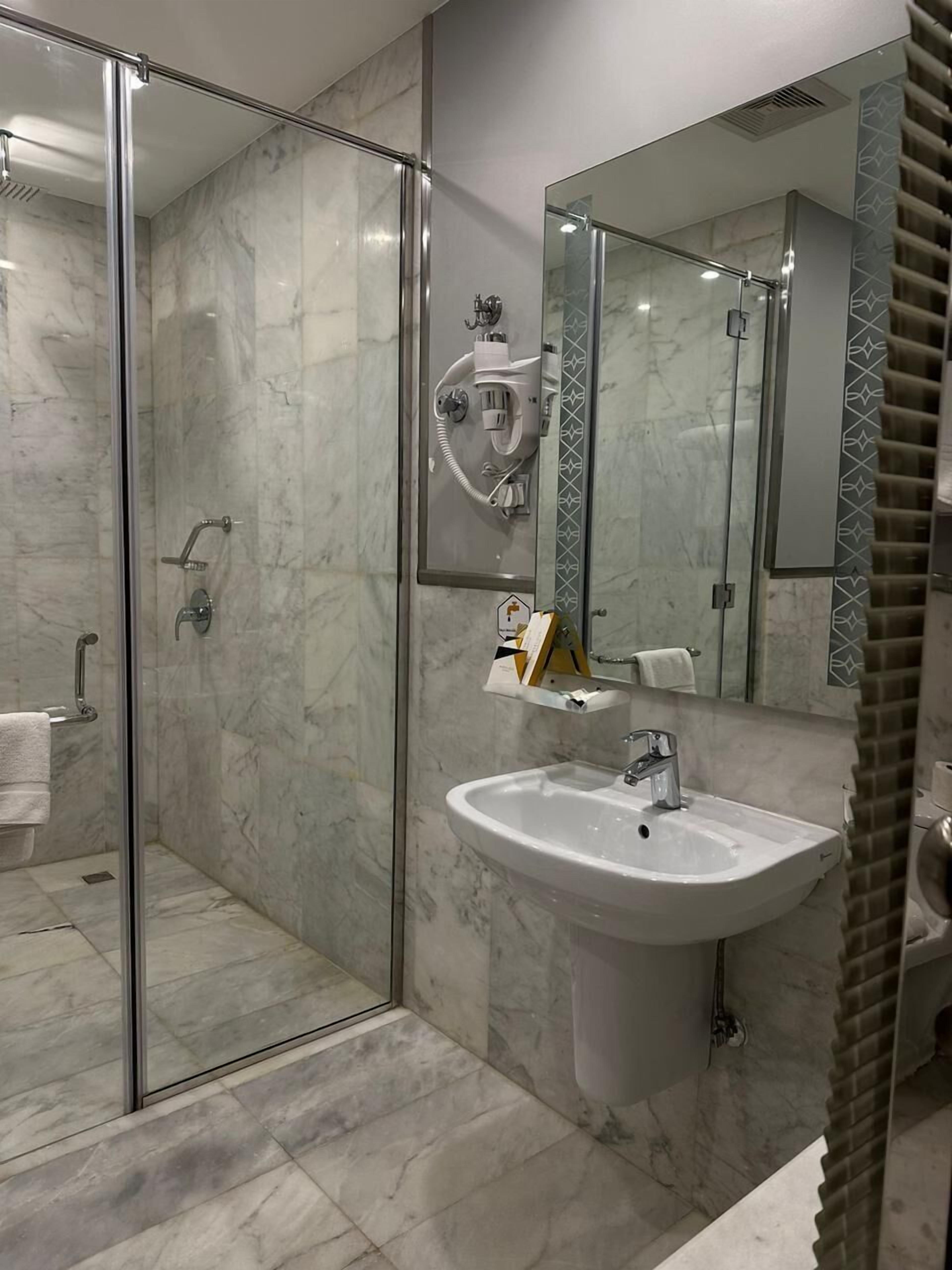 A modern bathroom with a glass-enclosed shower, a white sink, and a large mirror.