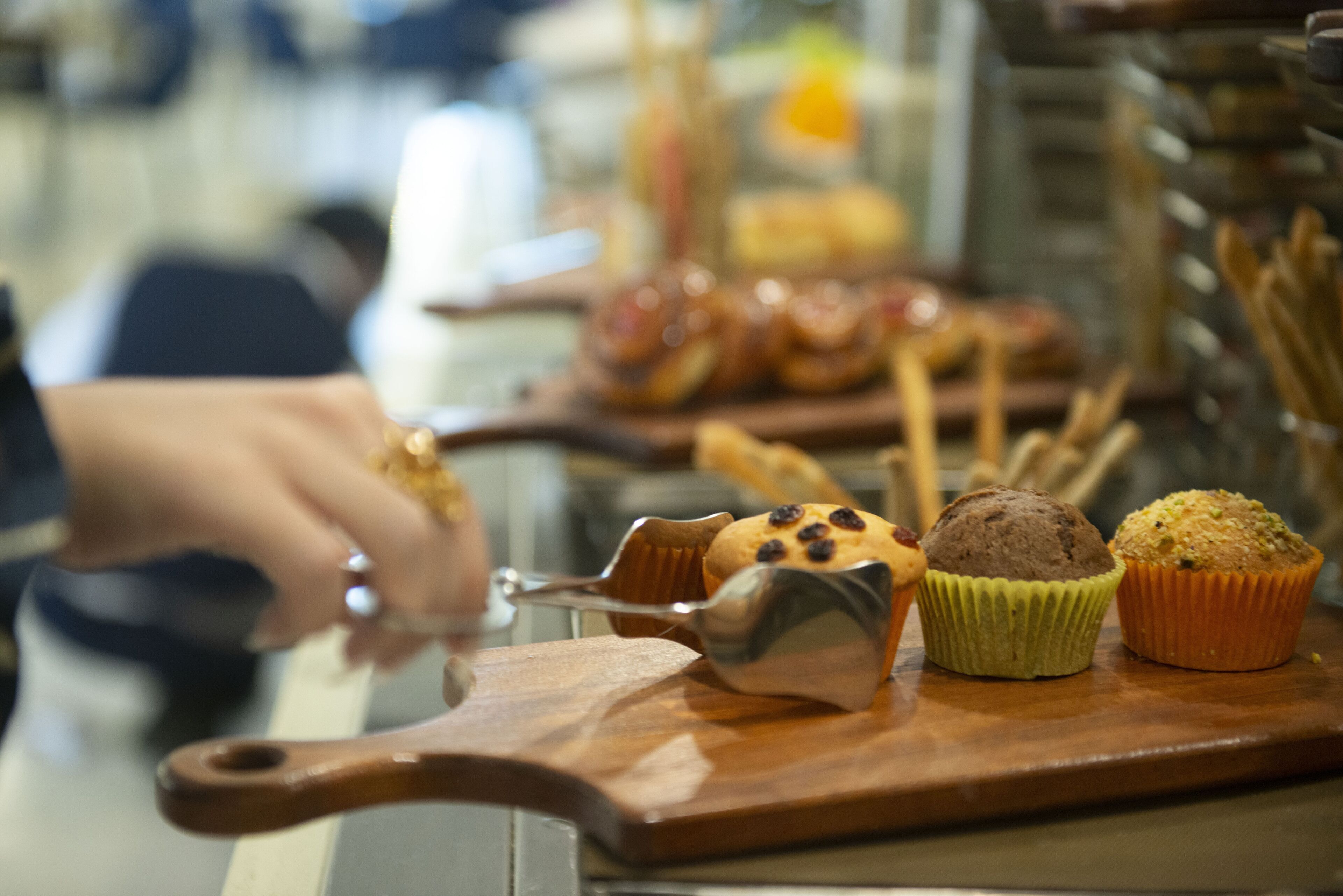 A wooden serving board with muffins and a muffin scoop.