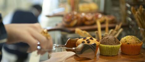 A wooden serving board with muffins and a muffin scoop.