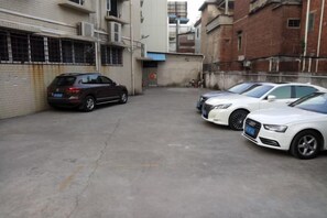 A parking area with several cars, including a black SUV and two white sedans. - Jade Business Hotel (Jade Street, Pingzhou, Foshan) (Foshan)