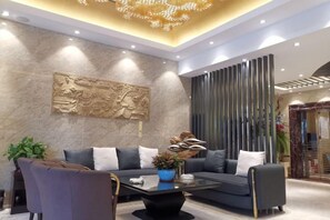 A modern living room with a sofa, coffee table, and decorative items. - Jade Business Hotel (Jade Street, Pingzhou, Foshan) (Foshan)