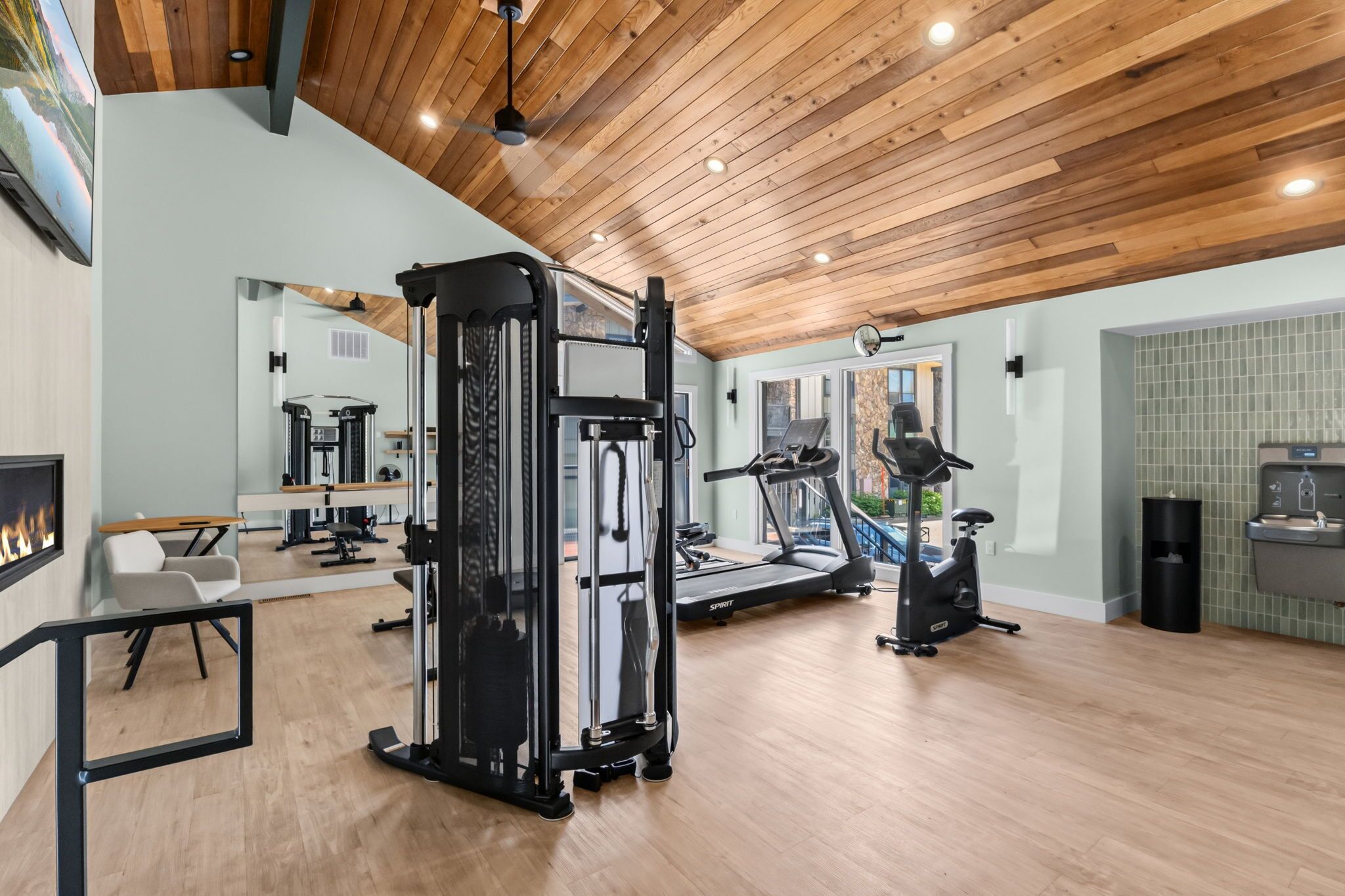 Ein großzügiger Heimfitnessraum mit vielfältigen Trainingsgeräten, darunter ein Laufband, ein Crosstrainer und Kraftgeräte.