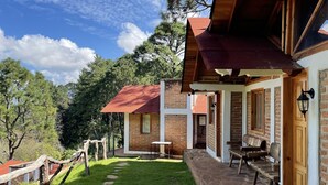 A rustic building with a covered porch, stone steps, and a brick exterior. - Cabañas los Pirineos (Mazamitla)