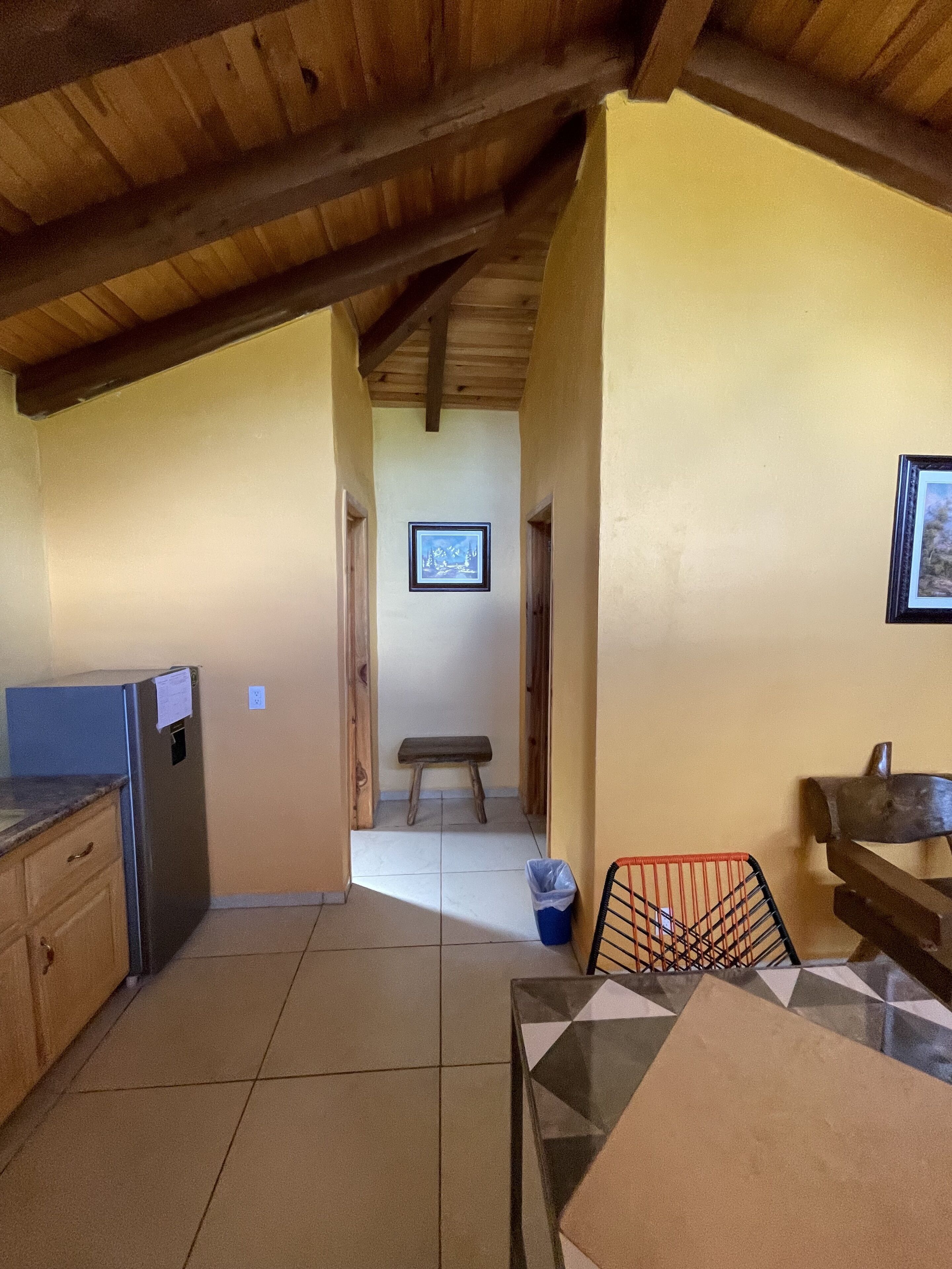 Una cocina con un refrigerador, un banco y una mesa.