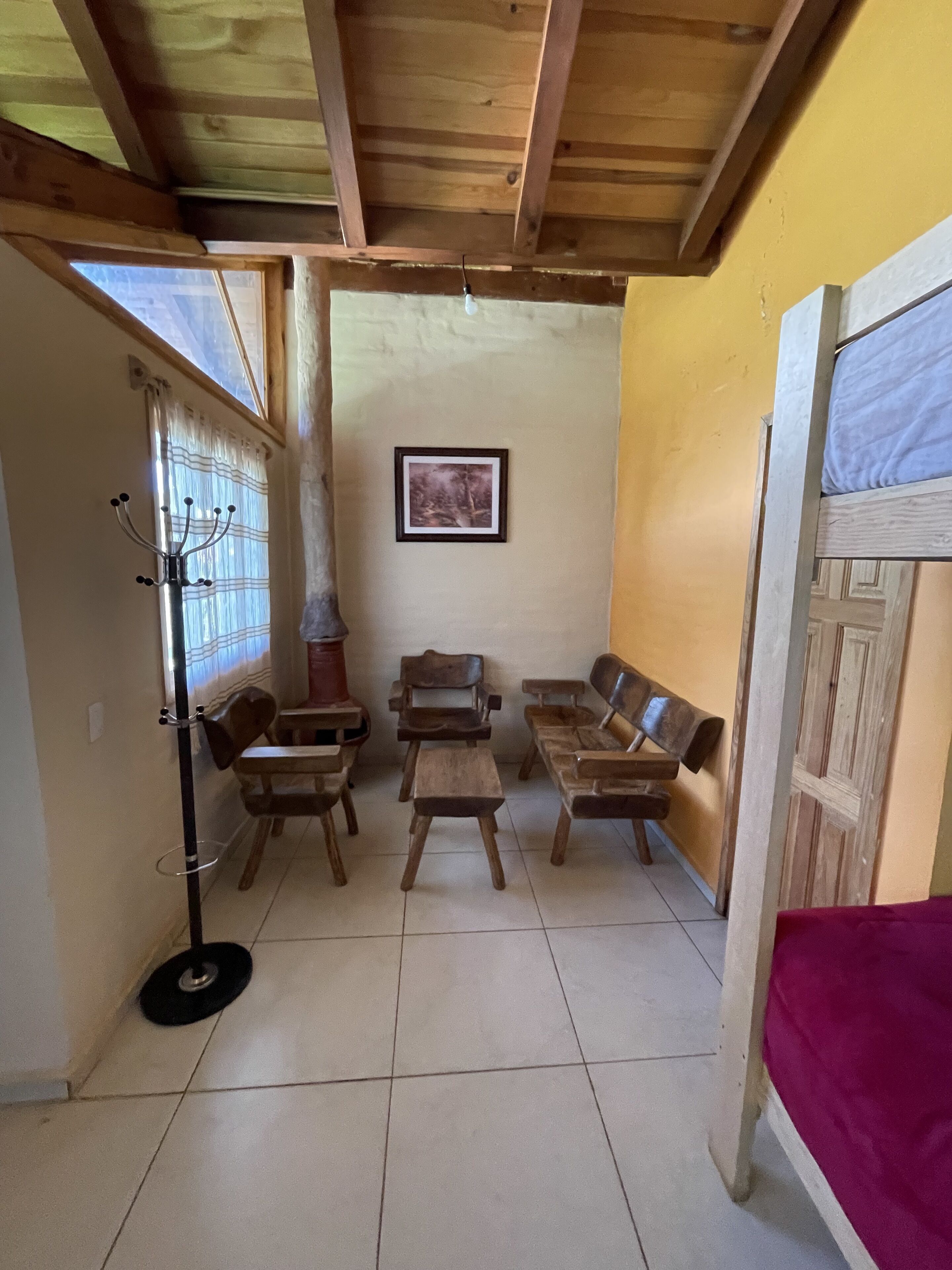 Una habitación con muebles de madera, un ventilador de techo, un cuadro en la pared y una ventana con cortinas.