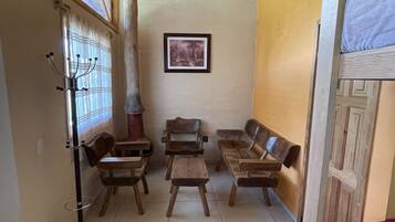 Una habitación con muebles de madera, un ventilador de techo, un cuadro en la pared y una ventana con cortinas.