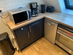 A modern kitchen with a microwave, coffee maker, toaster, dishwasher, and oven.