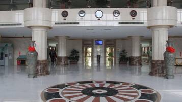 A lobby with a central circular floor design, multiple clocks, and a digital display.