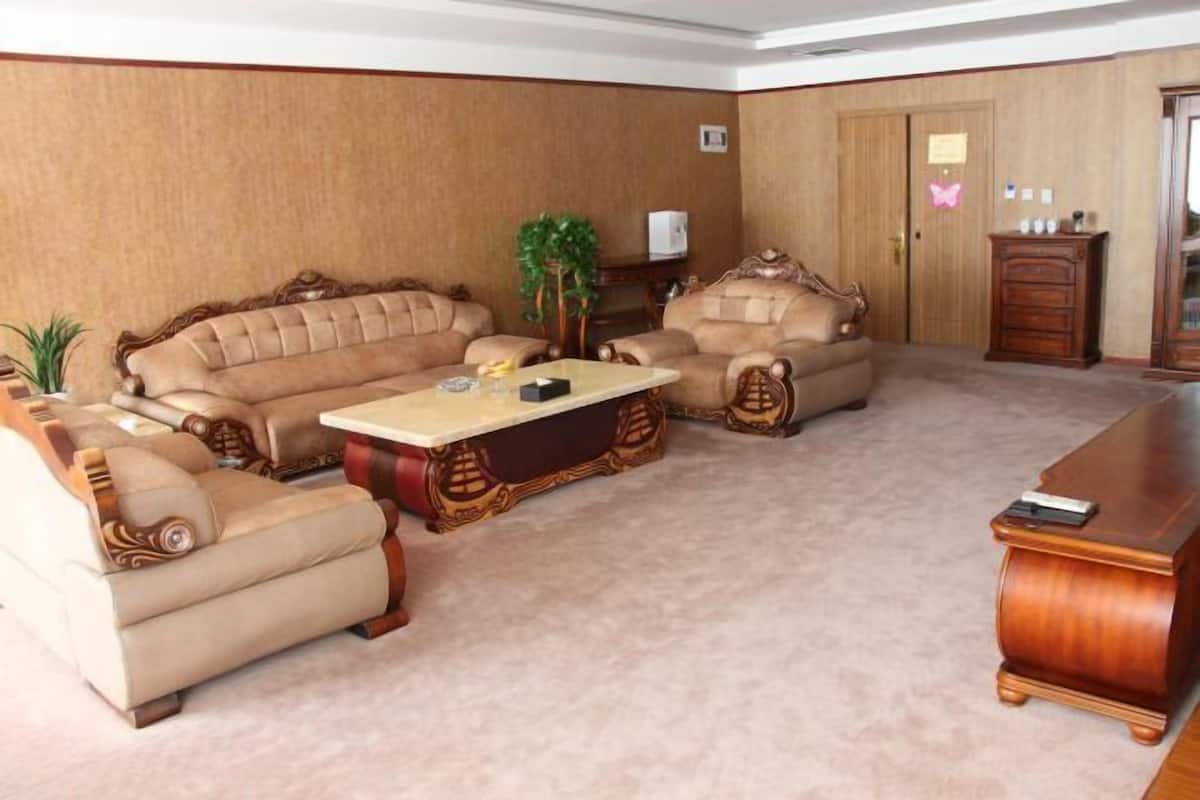 A living room with a beige sofa set, a wooden coffee table, and a wooden cabinet.